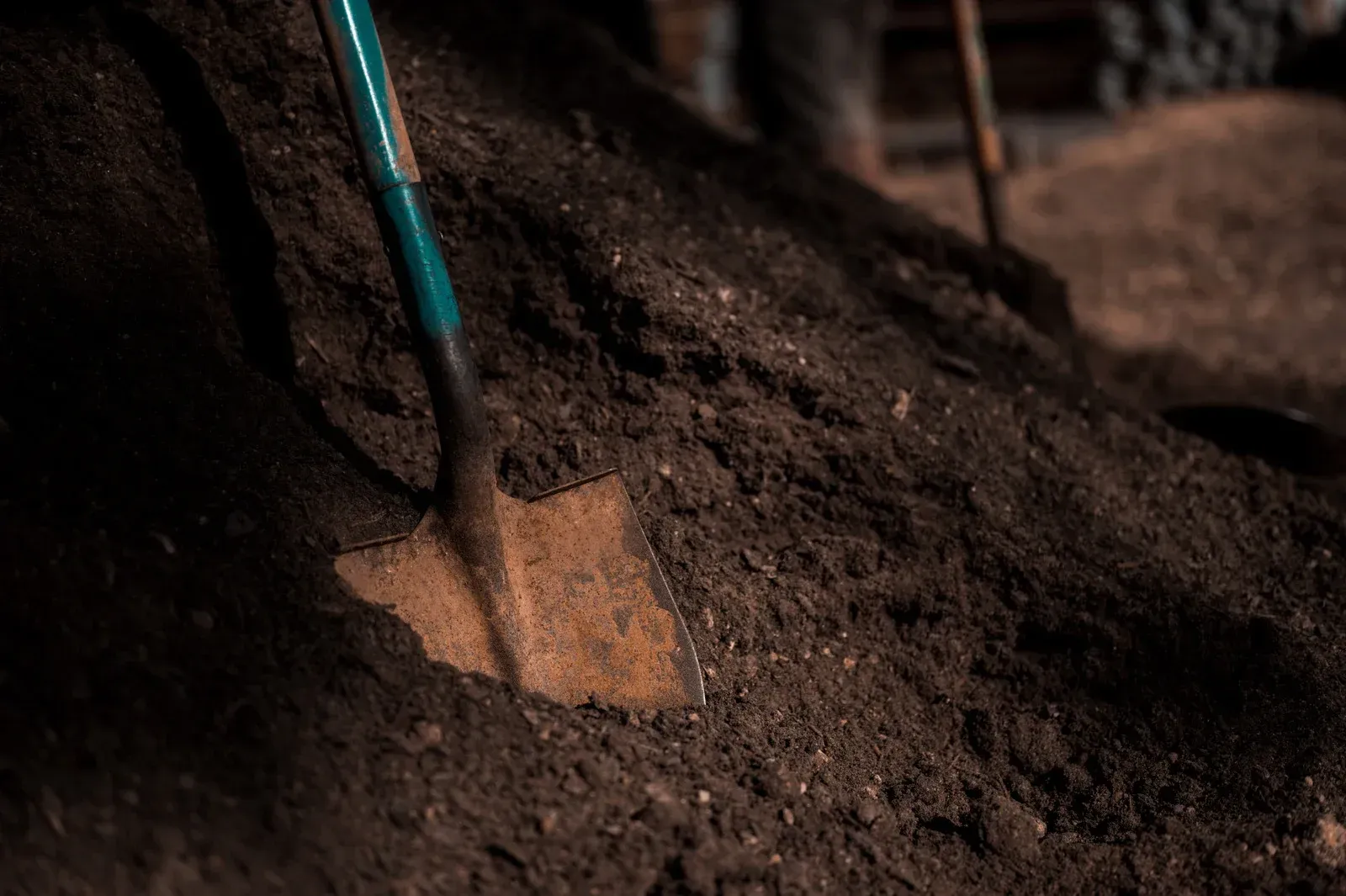 Close-up view of dark brown soil, with a rough, textured appearance, possibly compost.