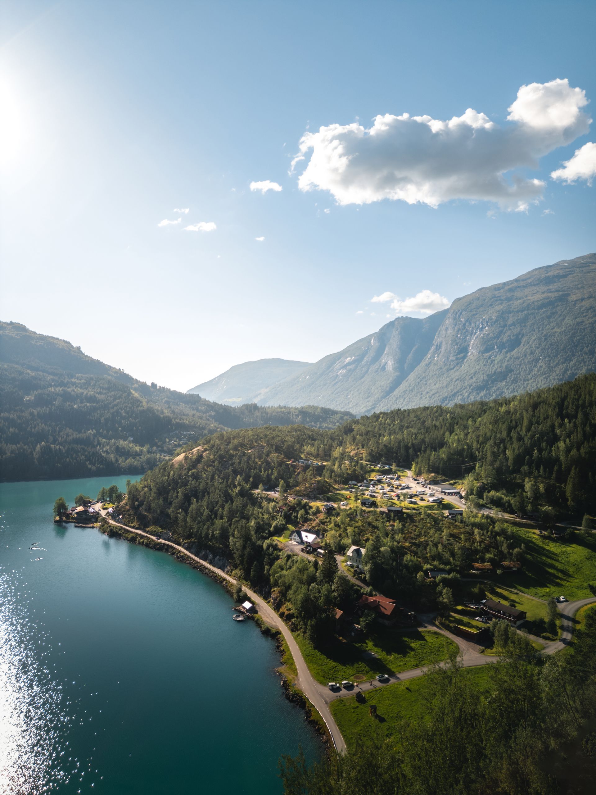Solbelyst landsby ved en innsjø omgitt av grønne fjell ved en blå innsjø