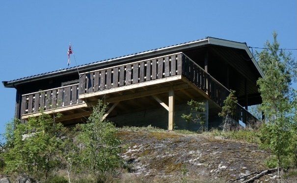 Trehytte på en steinete åsside under en klar blå himmel