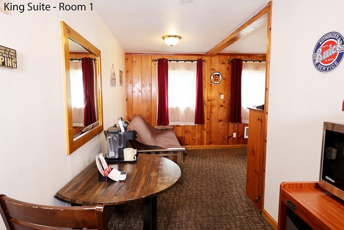 King suite hotel room with bed, desk, TV, and wood-paneled walls