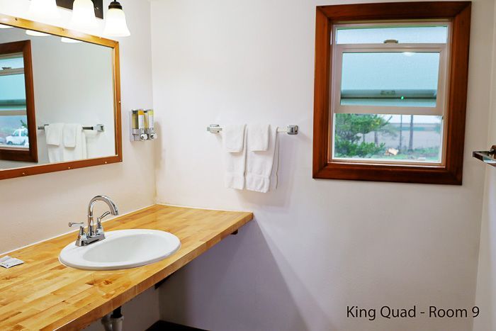 Bathroom with wood vanity, white sink, mirror, towel rack, and window overlooking the water.