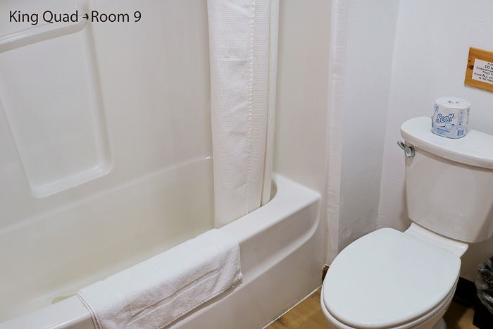 Bathroom with white bathtub, toilet, and shower curtain in a small hotel room