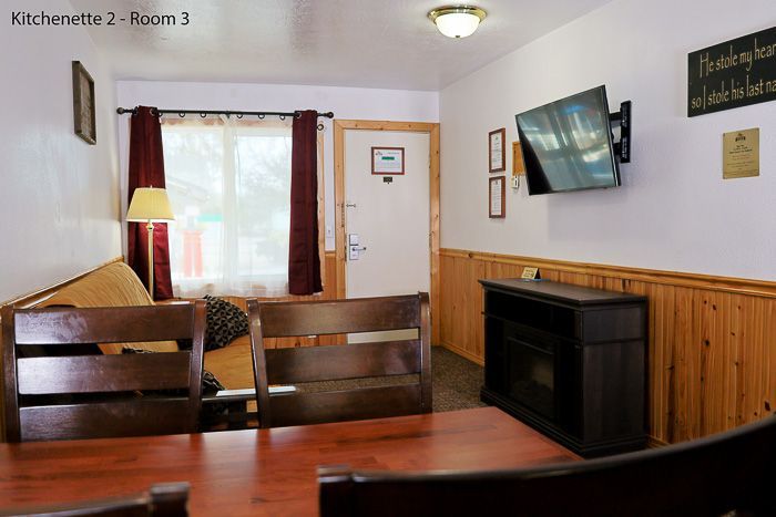 Cozy living room with brown furniture, wall-mounted TV, fireplace, and sliding glass door