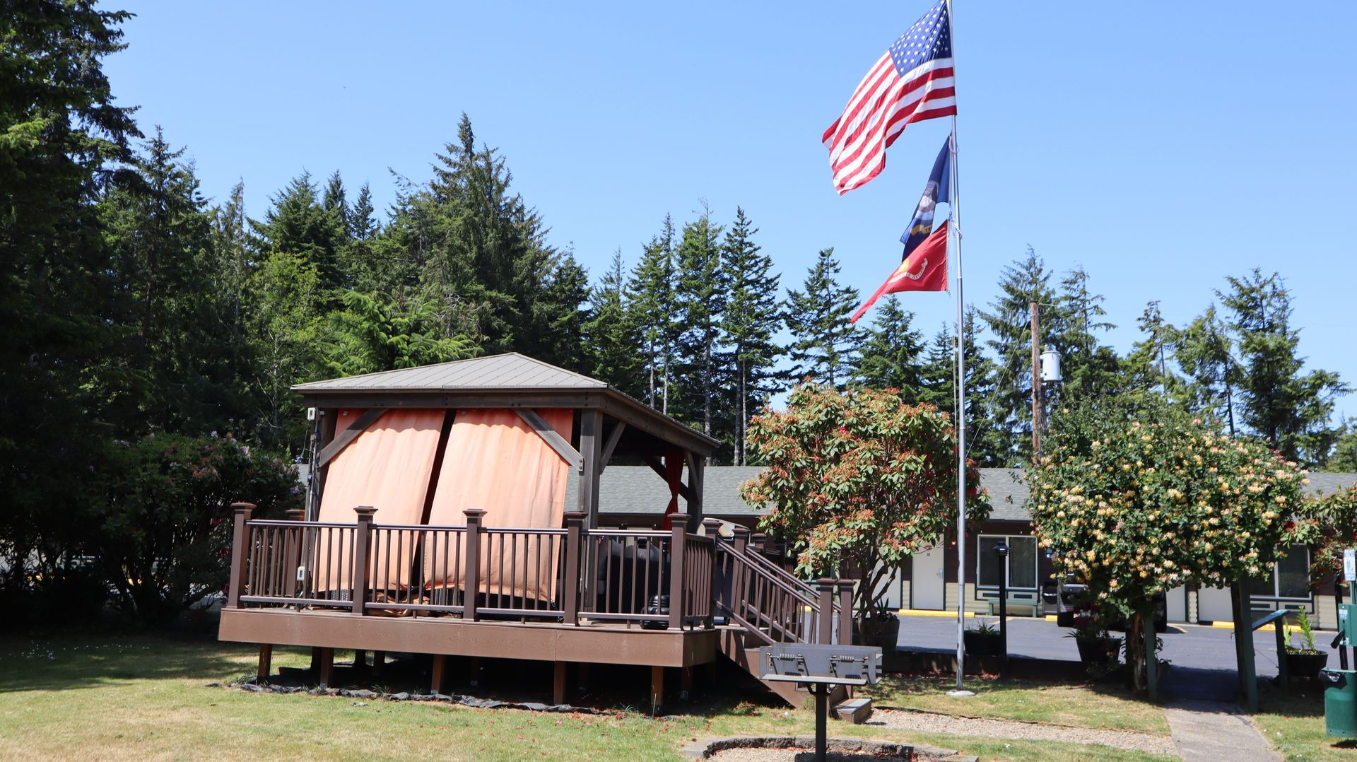 Cabin-like pavilion with flags and trees in a sunny park