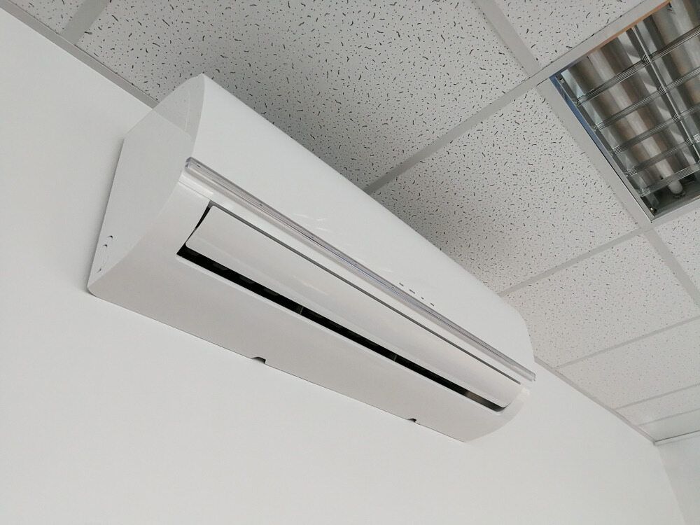 A White Air Conditioner is Mounted on a White Wall — Todd Hayes Refrigeration & Air Conditioning Pty Ltd in Yamba, NSW