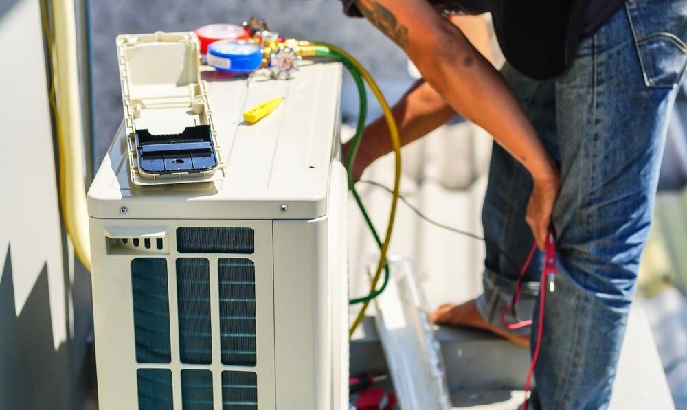 A Man is Working on an Air Conditioner Outside of a Building — Todd Hayes Refrigeration & Air Conditioning Pty Ltd in Kyogle, NSW