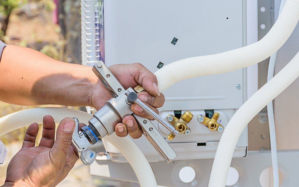 A Man is Working on an Air Conditioner With a Hose Attached to It — Todd Hayes Refrigeration & Air Conditioning Pty Ltd in Casino, NSW