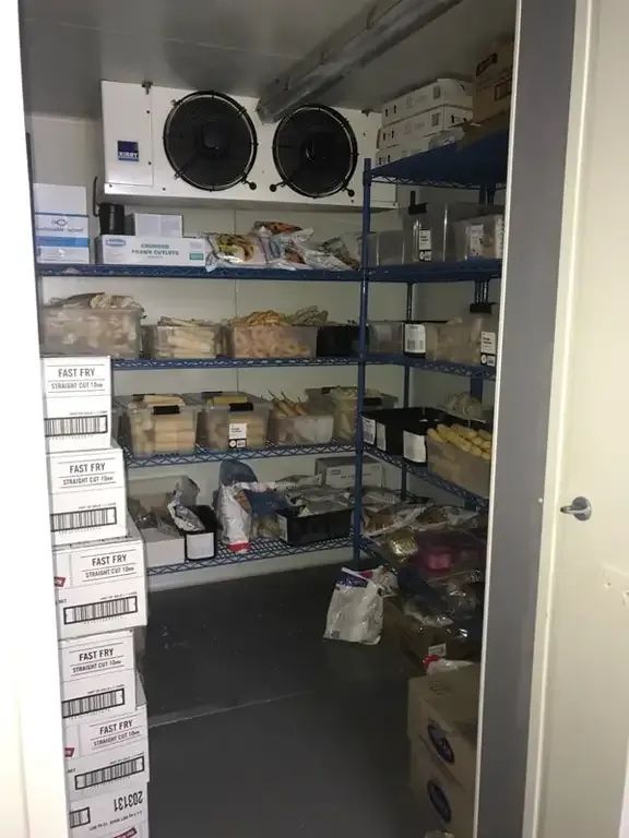 A Walk in Freezer Filled With Boxes and Shelves — Todd Hayes Refrigeration & Air Conditioning Pty Ltd in Kyogle, NSW