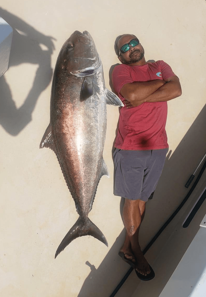 Fishing Destin, FL | Destin Harbor | Charter Boat Relentless | www.charterboatrelentless.com | A Luxury Charter Boat at Everyday Rates | 65' x 20' | A man is standing next to a large fish (Amberjack) on a boat.