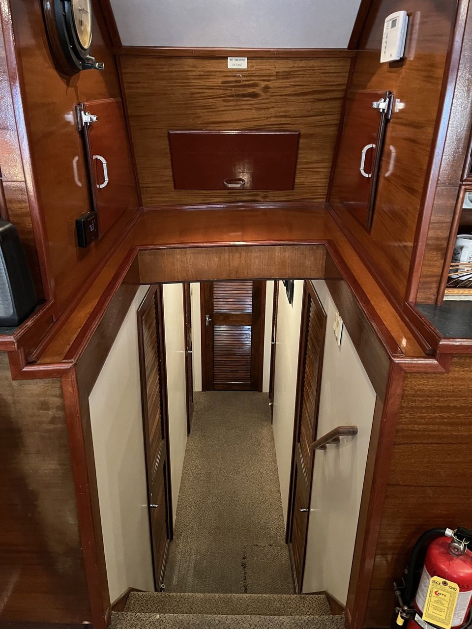 Fishing Destin, FL | Destin Harbor | Charter Boat Relentless | www.charterboatrelentless.com | A Luxury Charter Boat at Everyday Rates | 65' x 20' | A wooden hallway with stairs and a fire extinguisher in the corner.