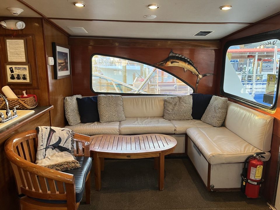 Fishing Destin, FL | Destin Harbor | Charter Boat Relentless | www.charterboatrelentless.com | A Luxury Charter Boat at Everyday Rates | 65' x 20' | A living room with a couch , chair , table and a fire extinguisher.