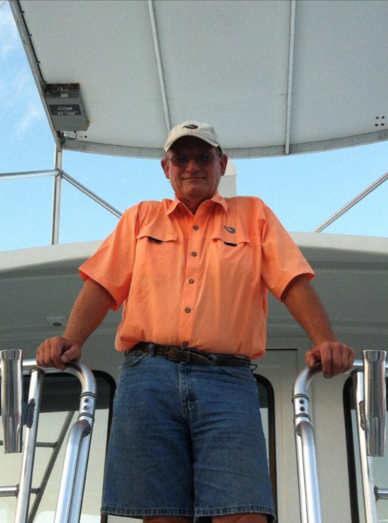 A man in an orange shirt is standing on a boat