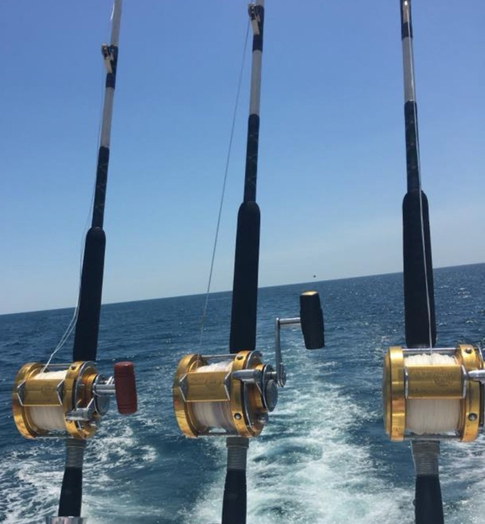 Three fishing rods are on a boat in the ocean