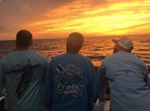 Fishing Destin, FL | Destin Harbor | Charter Boat Relentless | www.charterboatrelentless.com | A Luxury Charter Boat at Everyday Rates | 65' x 20' | Three men are standing on the Relentless, looking at the sunset over the ocean.
