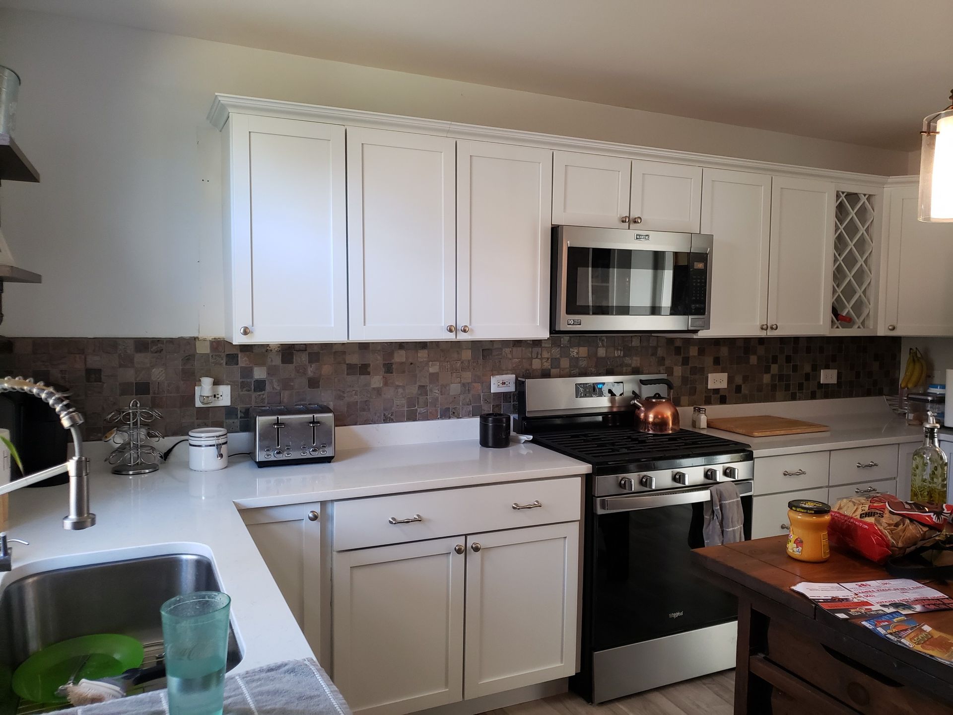 Modern kitchen with white cabinets, stainless steel appliances, and a countertop with fruit and small appliances