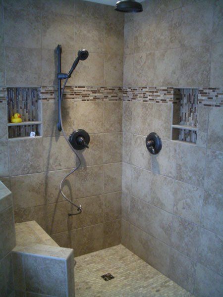 Walk-in tiled shower with built-in niches, black fixtures, and wall-mounted showerhead