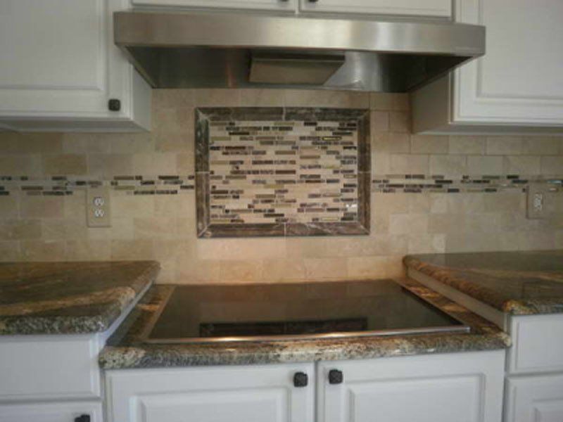 Modern kitchen with stainless steel stove, range hood, and tiled backsplash between granite counters