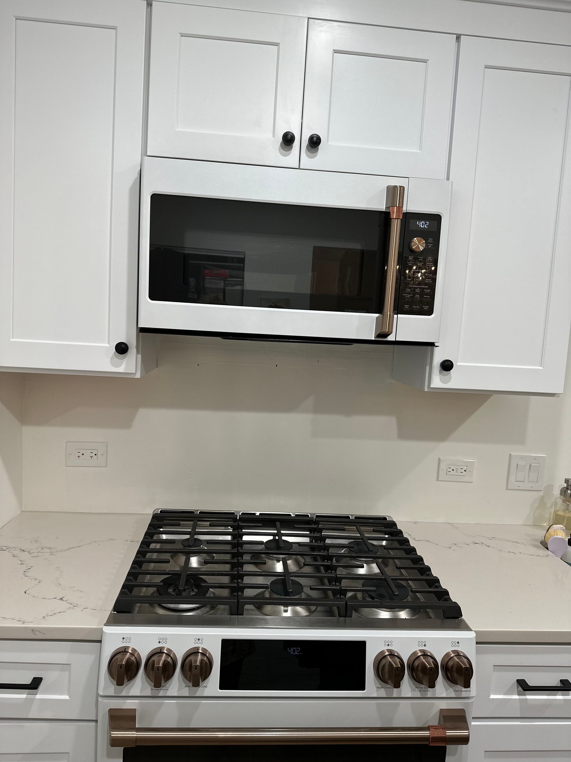Kitchen with white cabinets and a stainless steel gas range below a built-in microwave.
