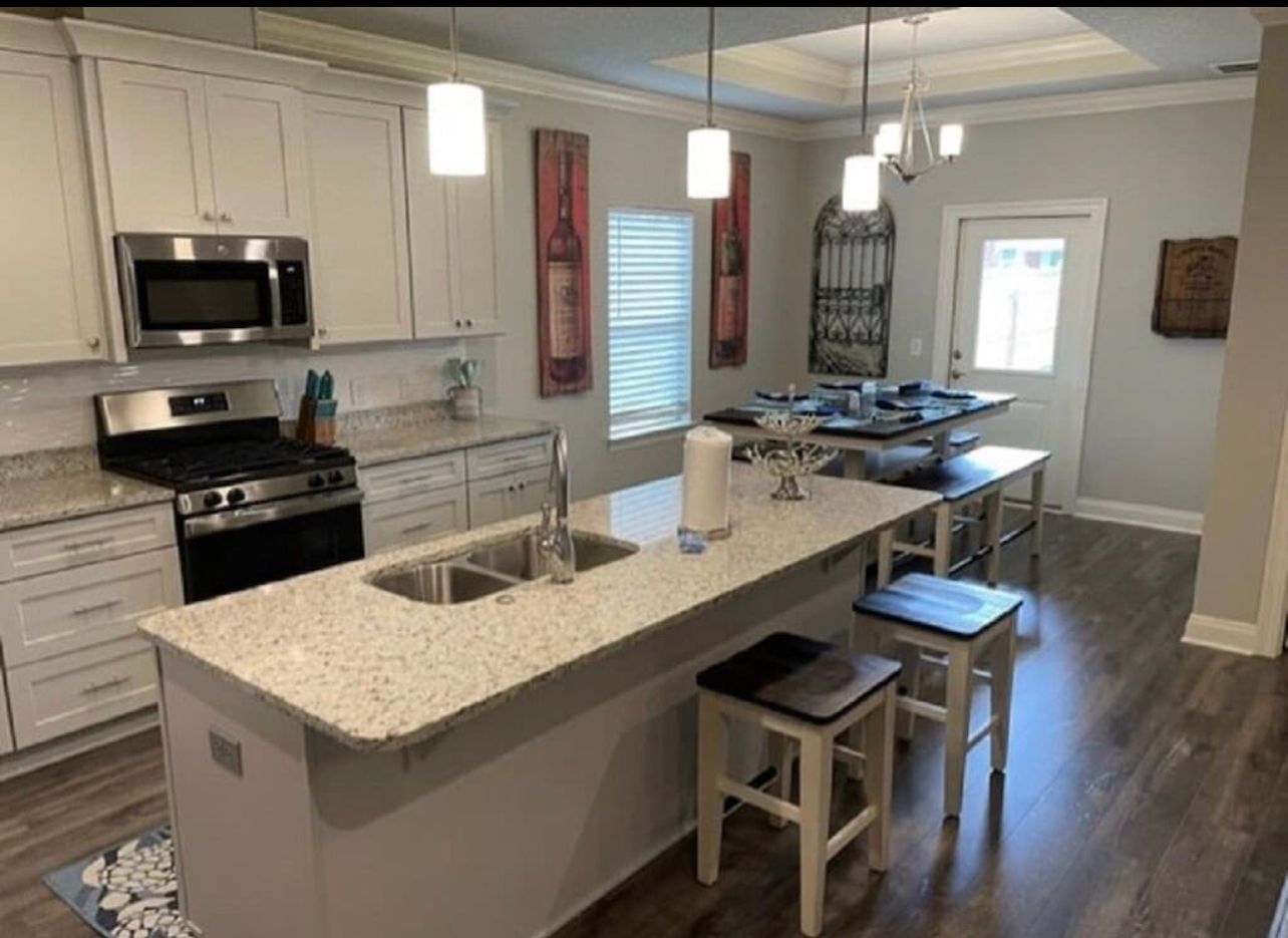 Modern kitchen with white cabinets, granite island, stainless appliances, and stools by the counter
