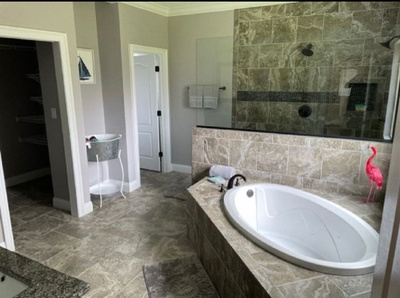 Modern bathroom with tiled walk-in tub, glass shower, and stone flooring