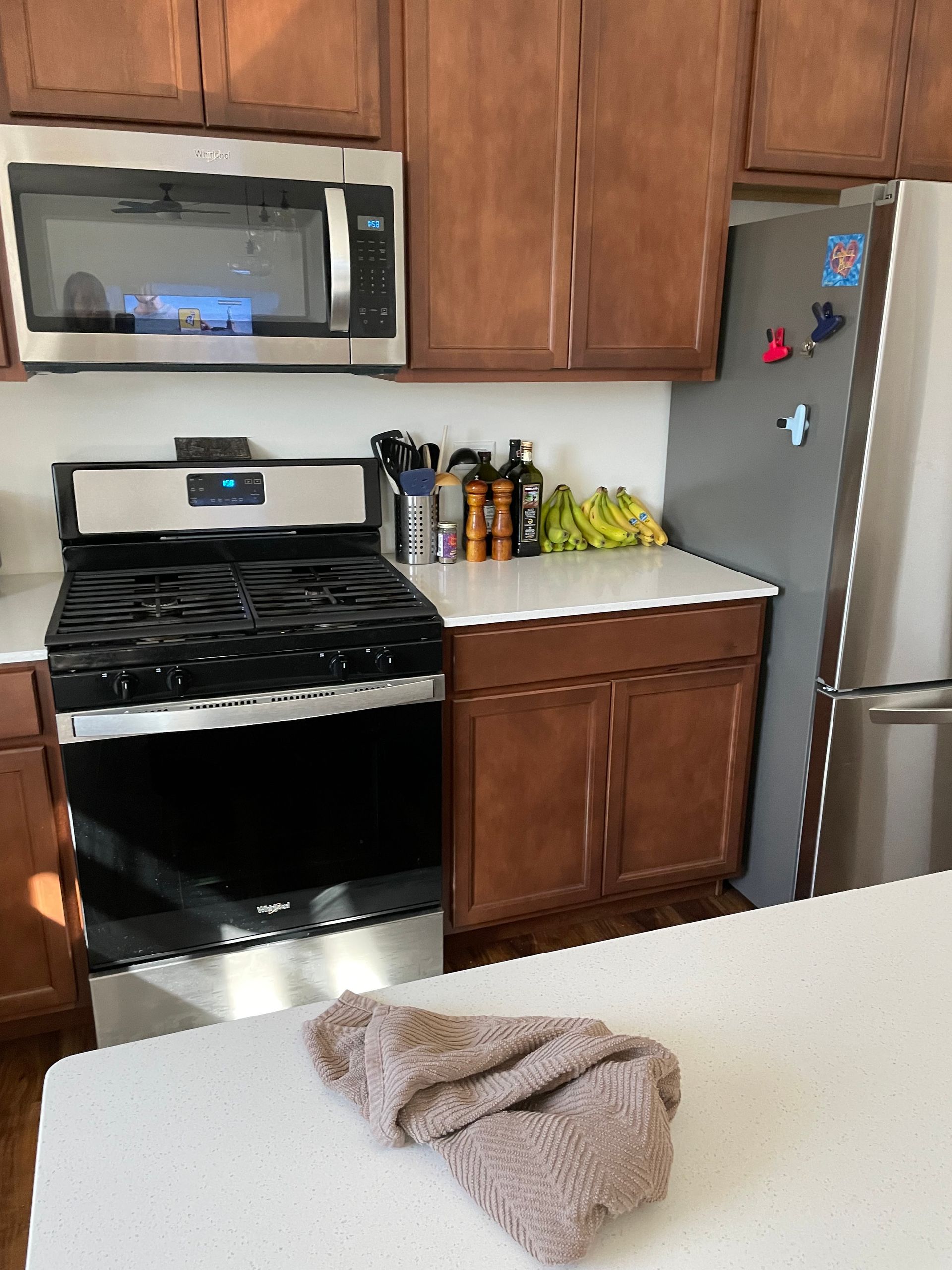 Kitchen with stainless steel appliances, brown cabinets, and a towel on the counter.