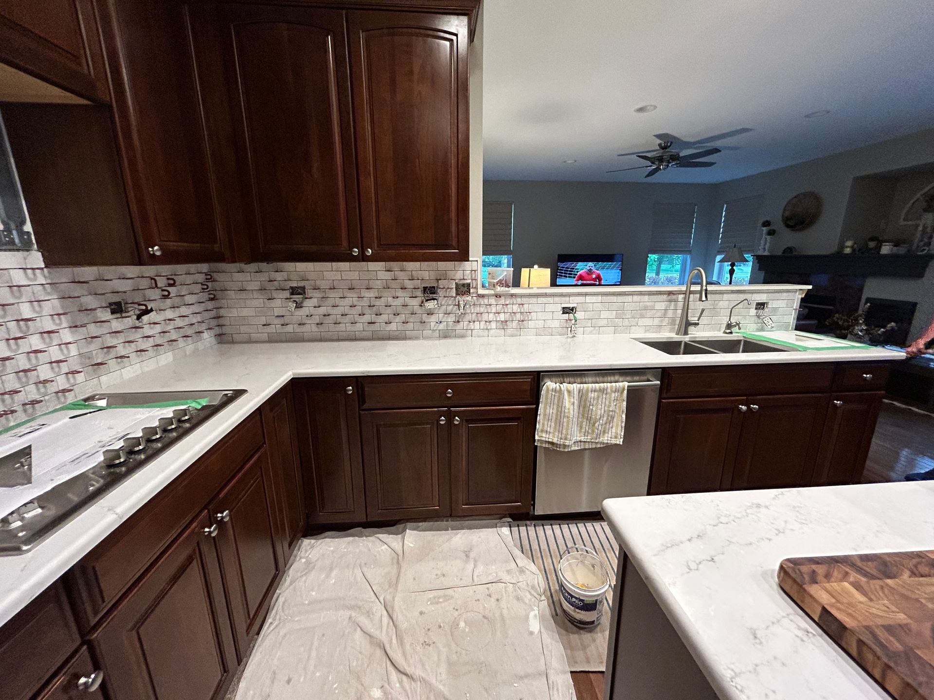 Modern kitchen with dark wood cabinets, light marble countertops, and a white tile backsplash.