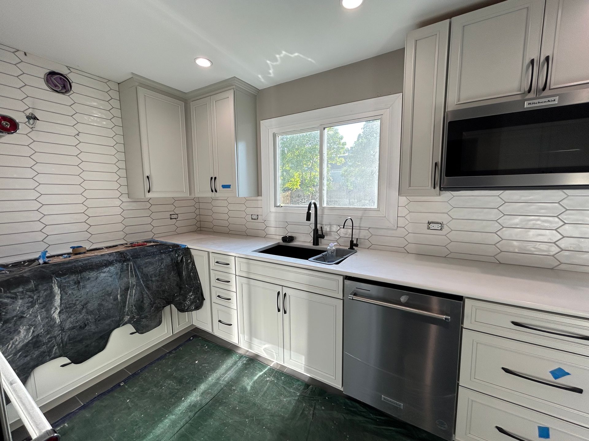 Modern kitchen with white cabinets, black granite counters, stainless appliances, and a window above the sink