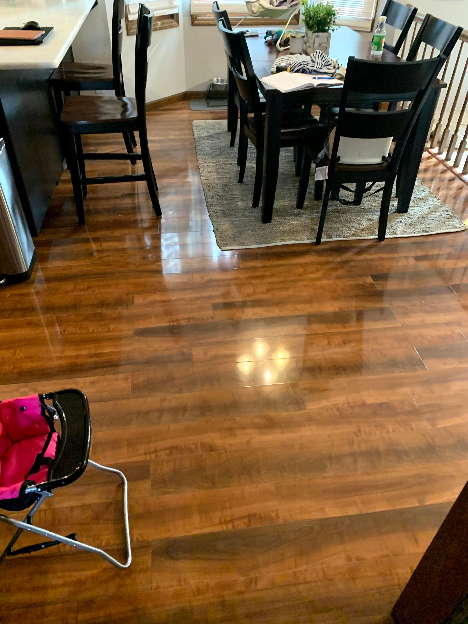 Dining area with dark wood table and chairs on a patterned rug, beside a glossy hardwood floor.