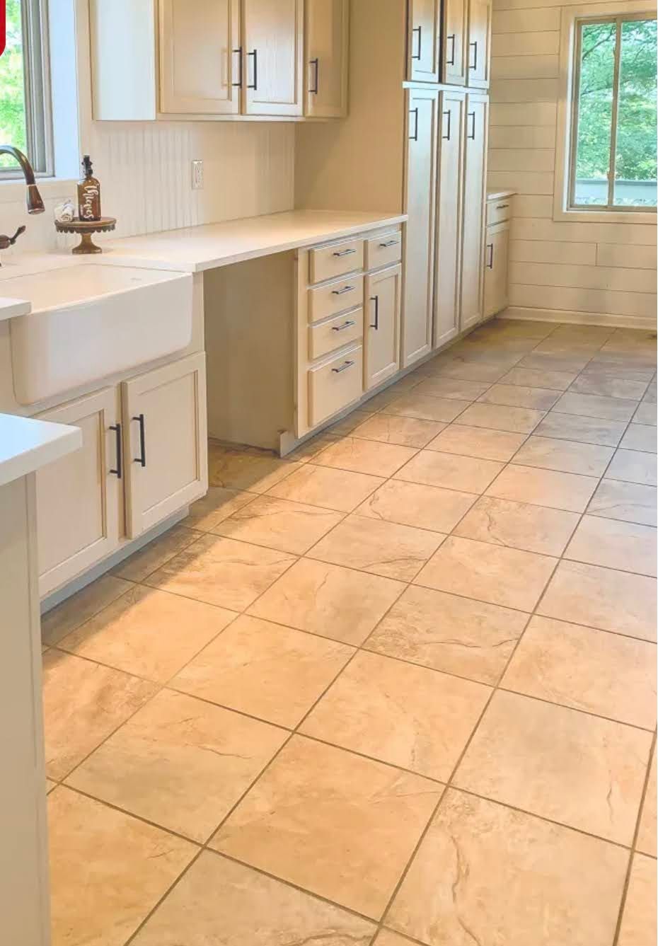 Bright kitchen with cream cabinets, tiled floor, and a window at the far end.