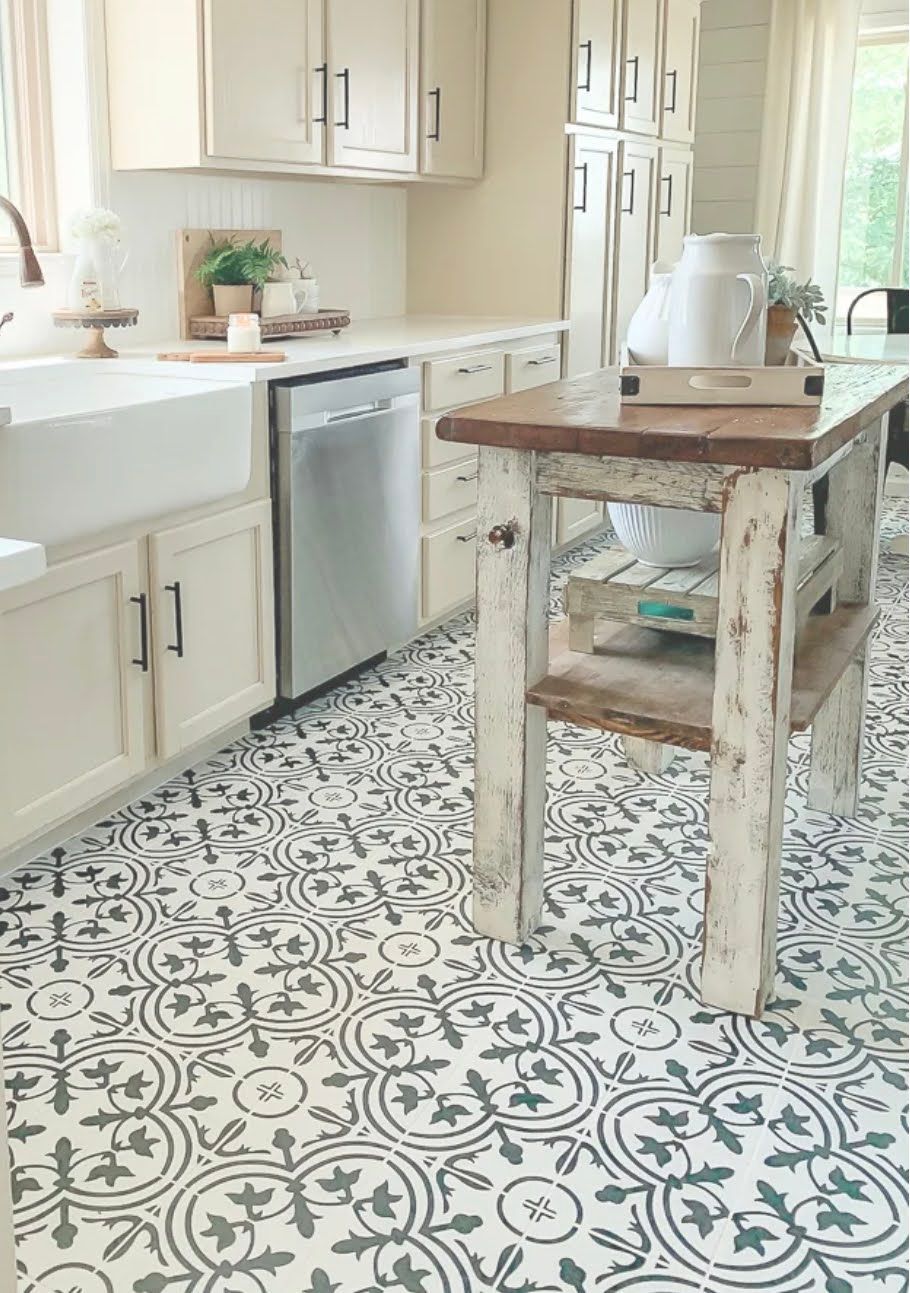 Bright kitchen with patterned tile floor, white cabinets, a wooden island, and a sink by the window.