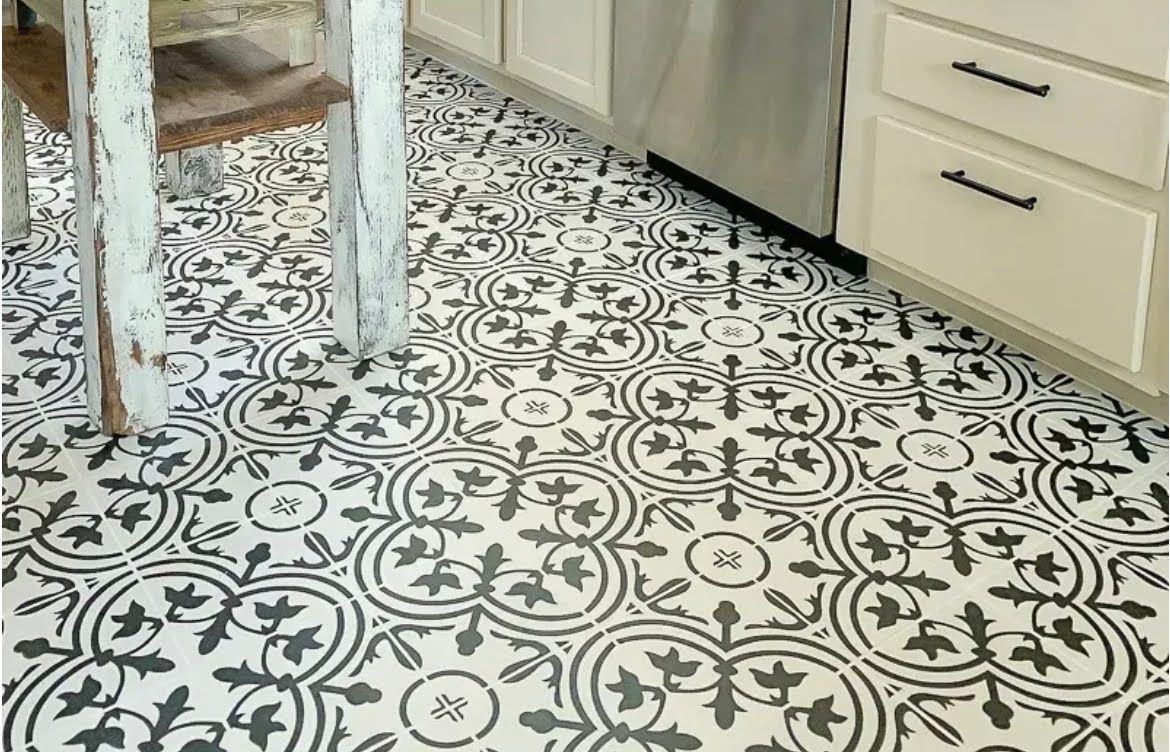 Patterned kitchen floor with black-and-white tile, white cabinets, and a wooden table leg in view