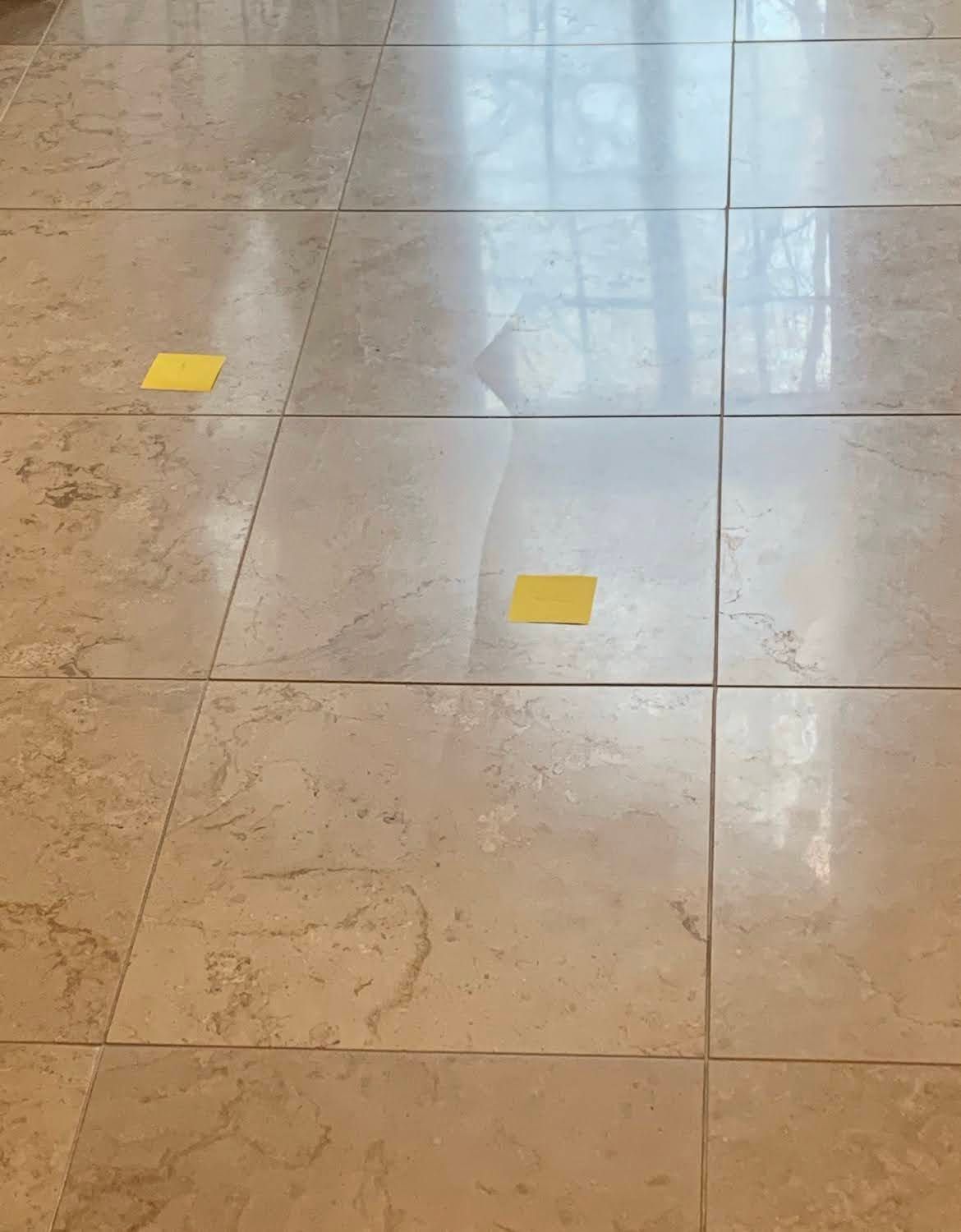 Polished tile floor with two small yellow markers, lit by window reflections.