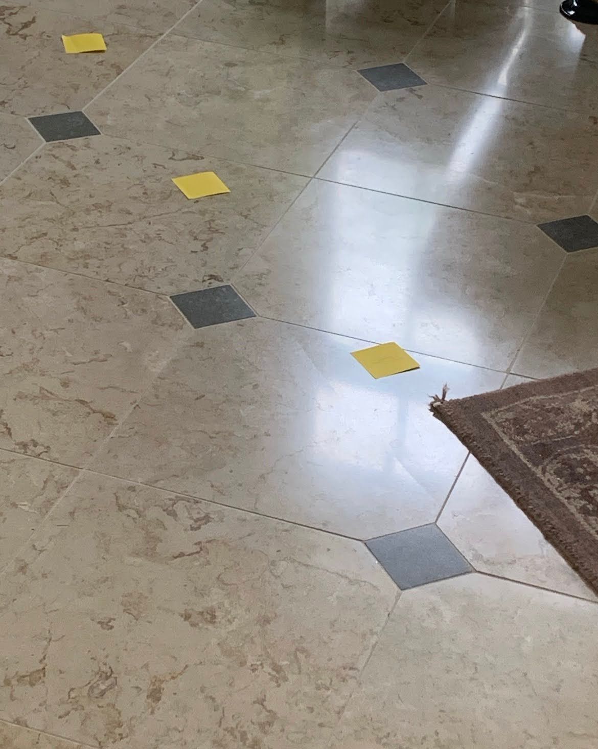 Tiled floor with yellow and gray diamond inlays beside a brown rug edge