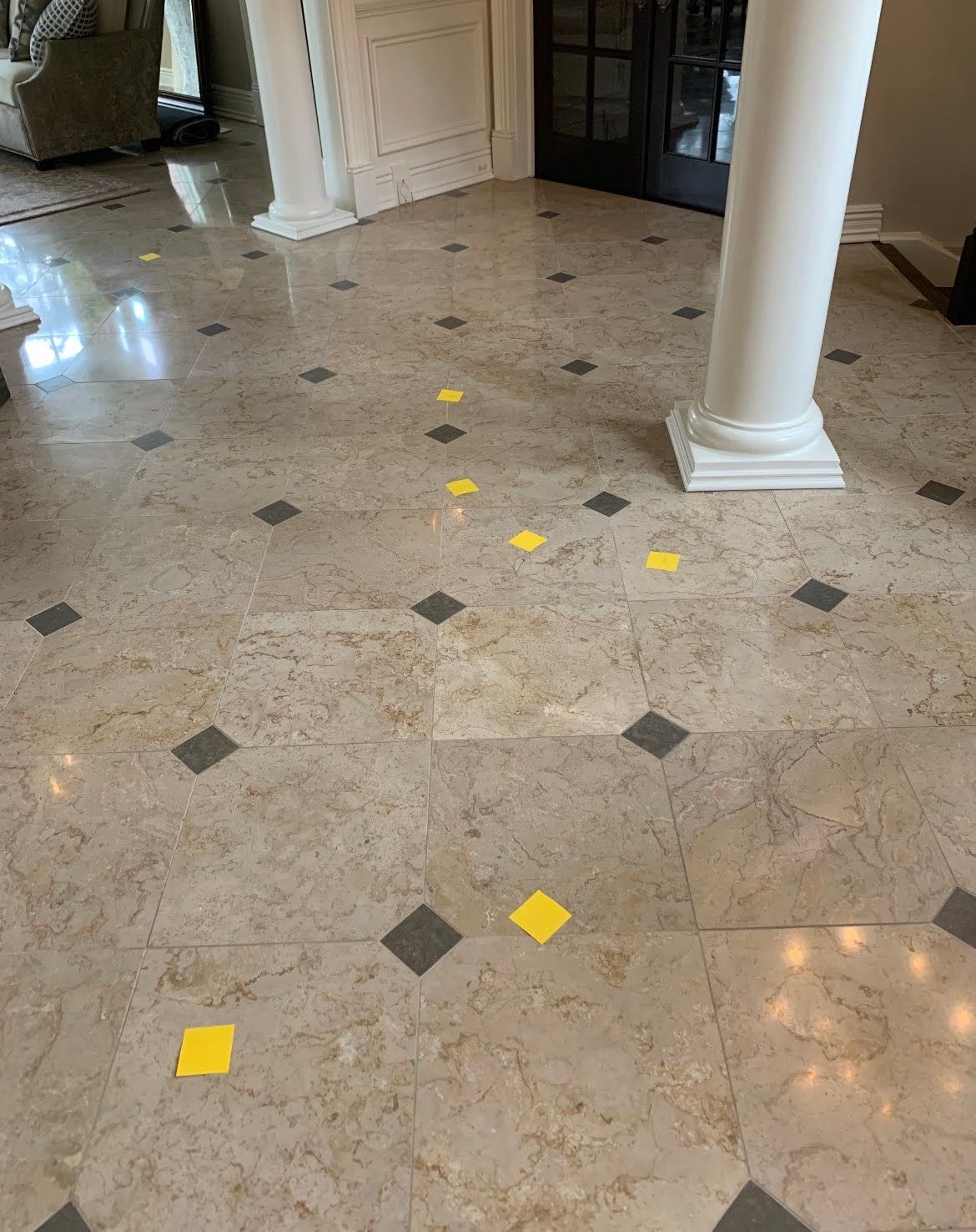 Marble foyer floor with yellow tape markers and dark diamond tiles near white columns