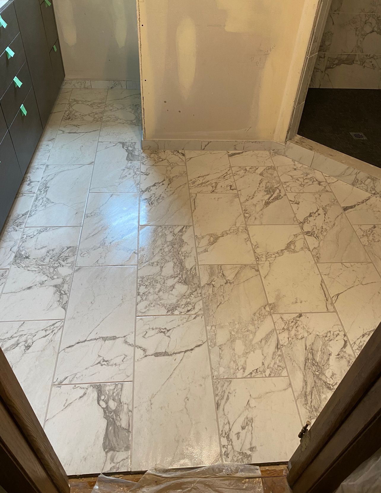 Marble-tiled bathroom floor with a narrow doorway and hallway visible