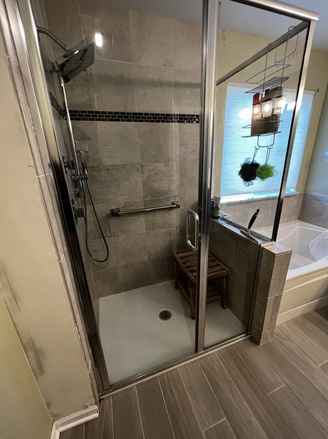 Walk-in shower with glass door, tiled walls, built-in bench, and rainfall showerhead in a bathroom