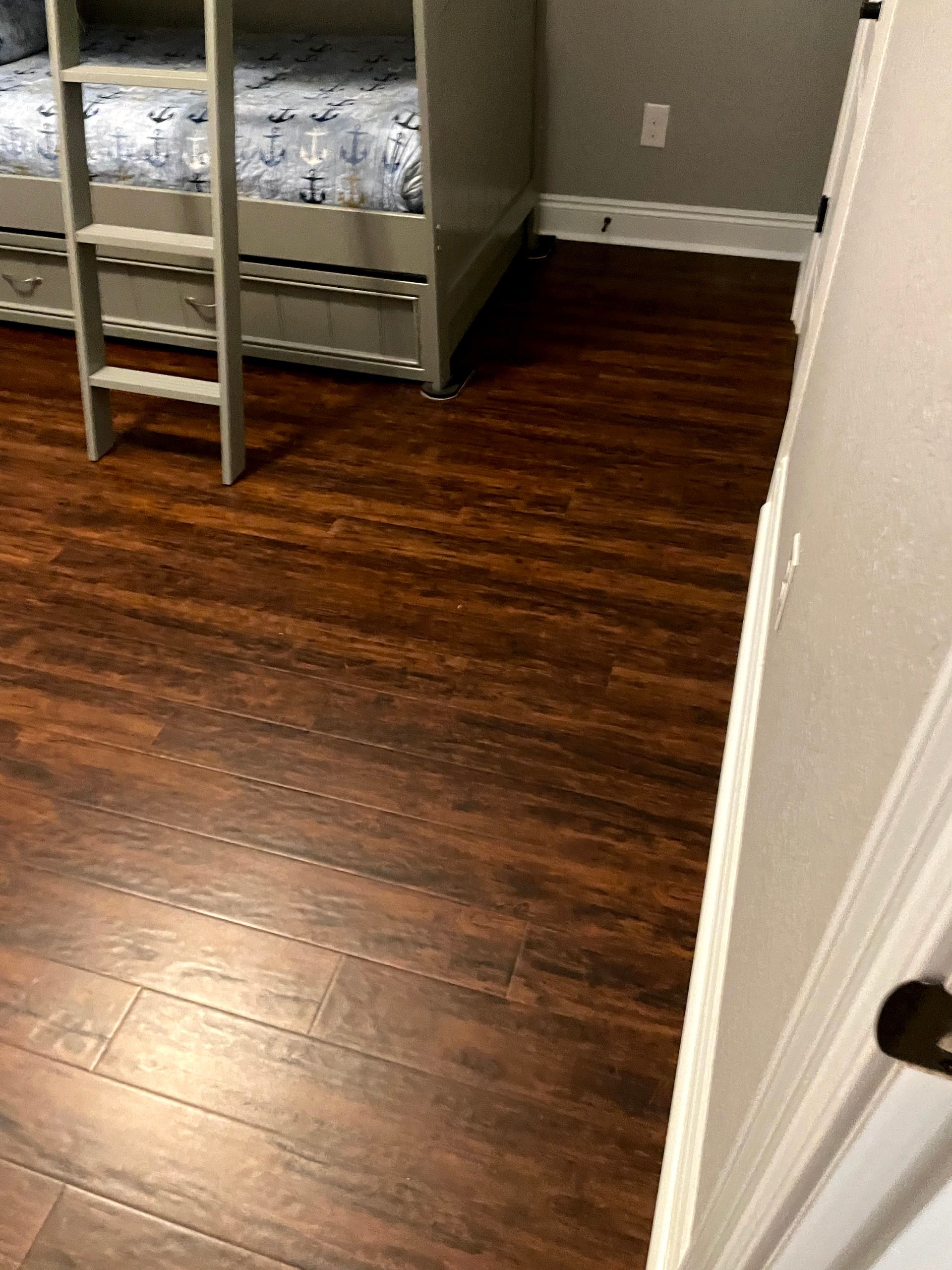 Small bedroom with dark wood floor, bunk bed, and open doorway.