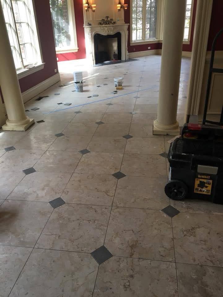 Empty room with marble floor, fireplace, and columns; cleaning supplies near the right side.