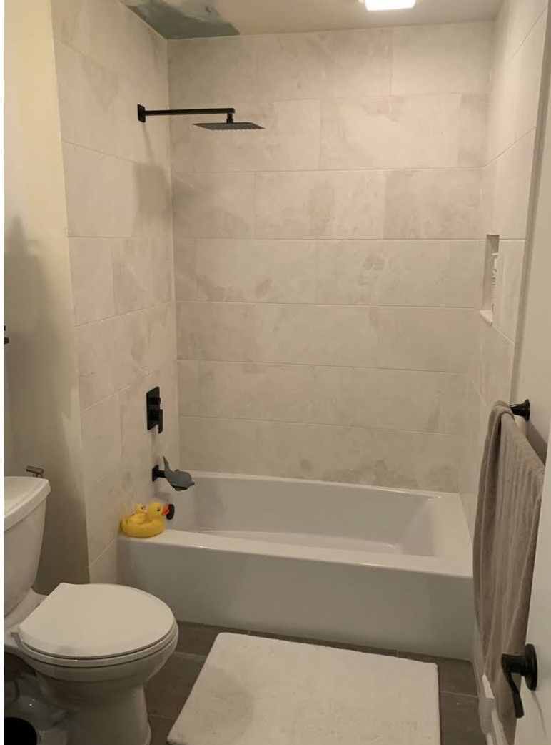 Small bathroom with a bathtub, toilet, towel rack, and white tiled walls.