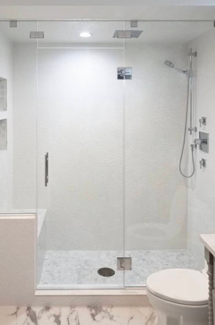 Modern bathroom with a glass walk-in shower, white tile, and a toilet on the right.