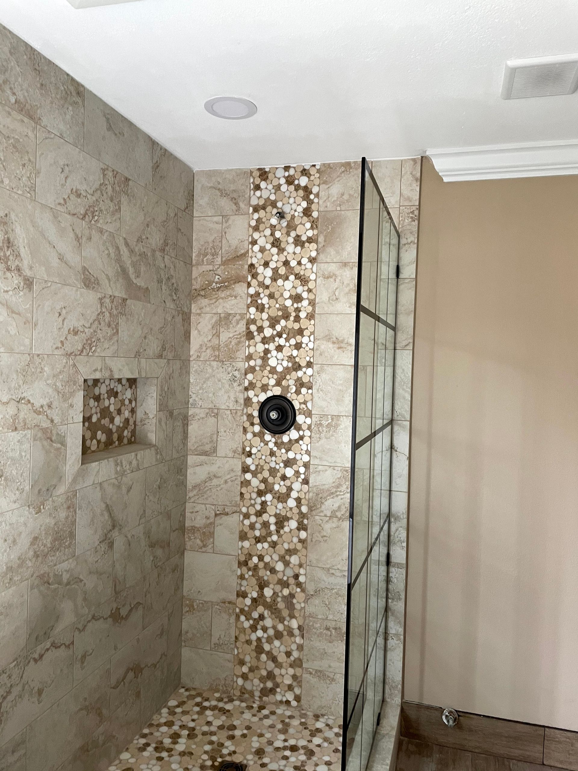 Bathroom shower with marble tile, mosaic accent strip, and glass shower partition