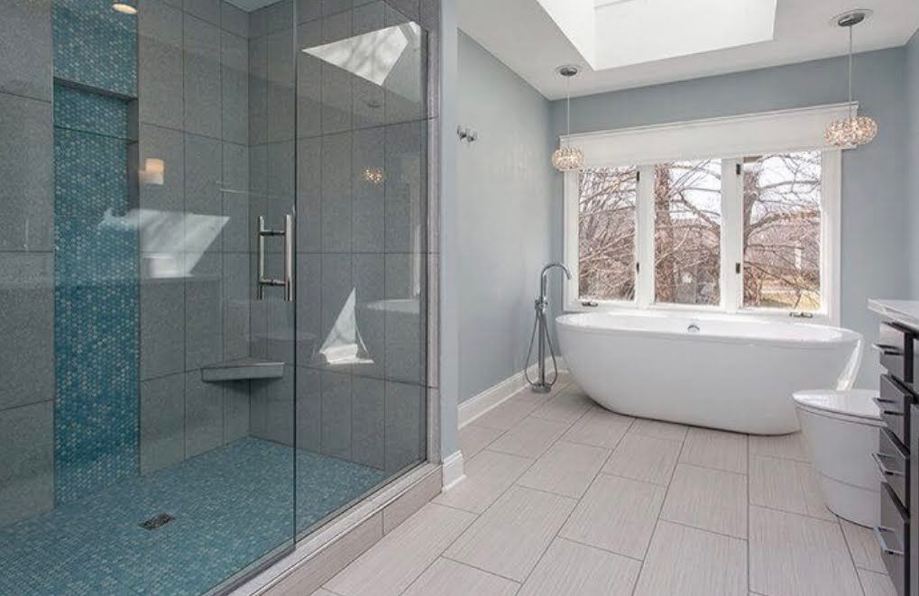 Modern bathroom with glass shower, freestanding tub, and large window letting in natural light