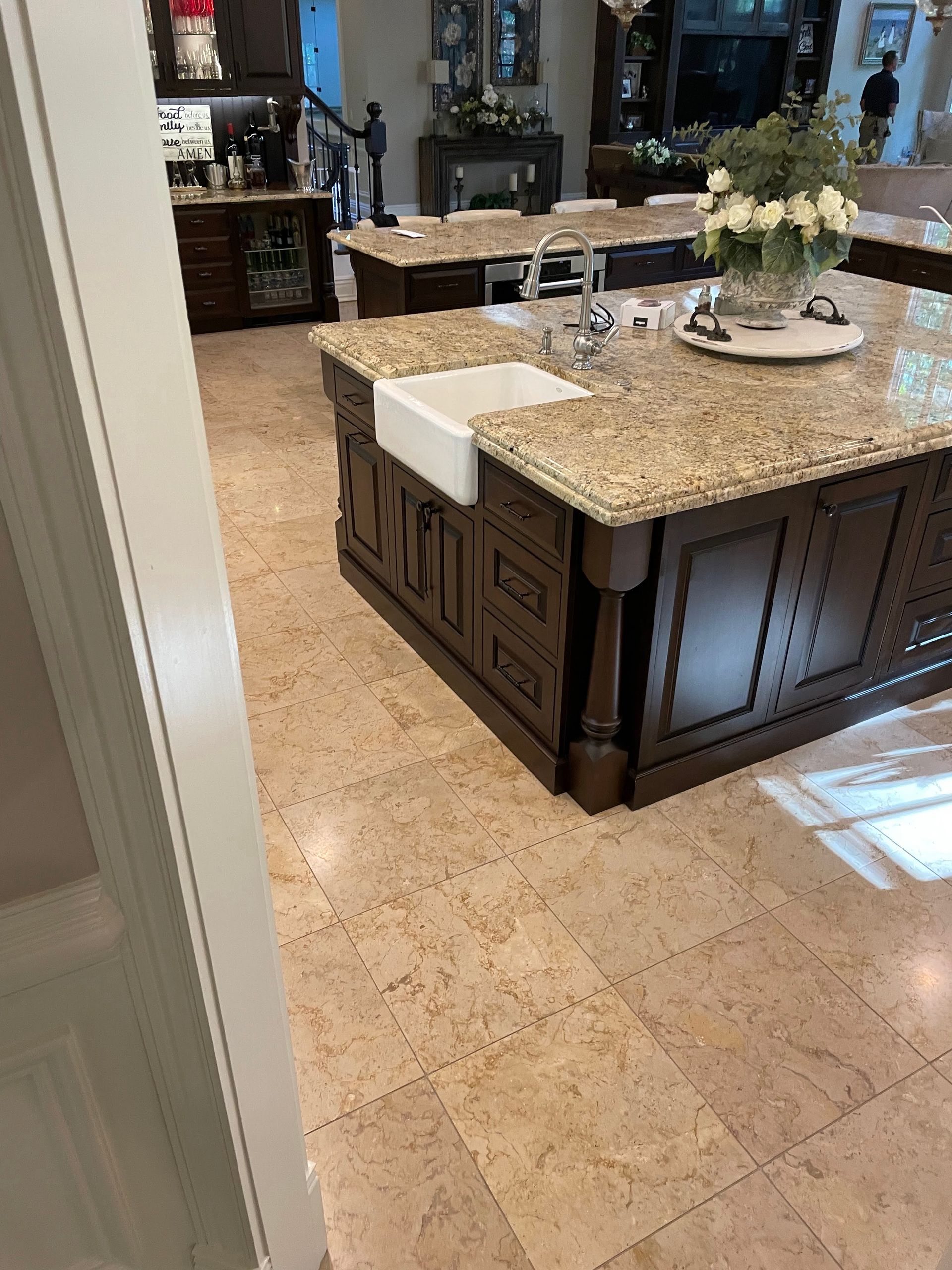 Kitchen with granite island, tiled floor, and a vase of flowers on a tray.