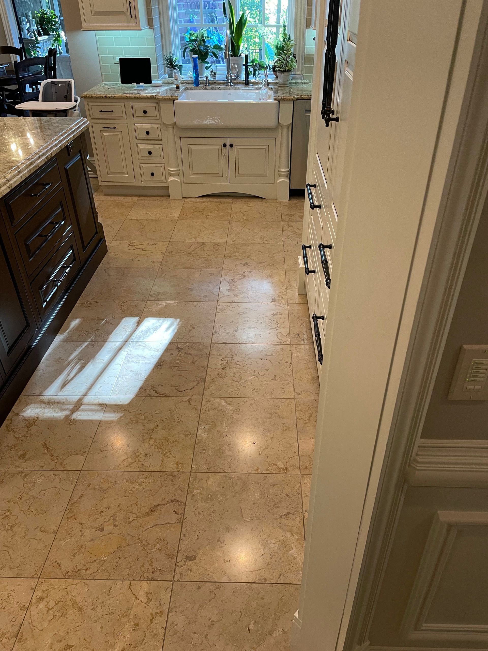 Kitchen hallway with beige tile floor, white cabinets, and bright window light.