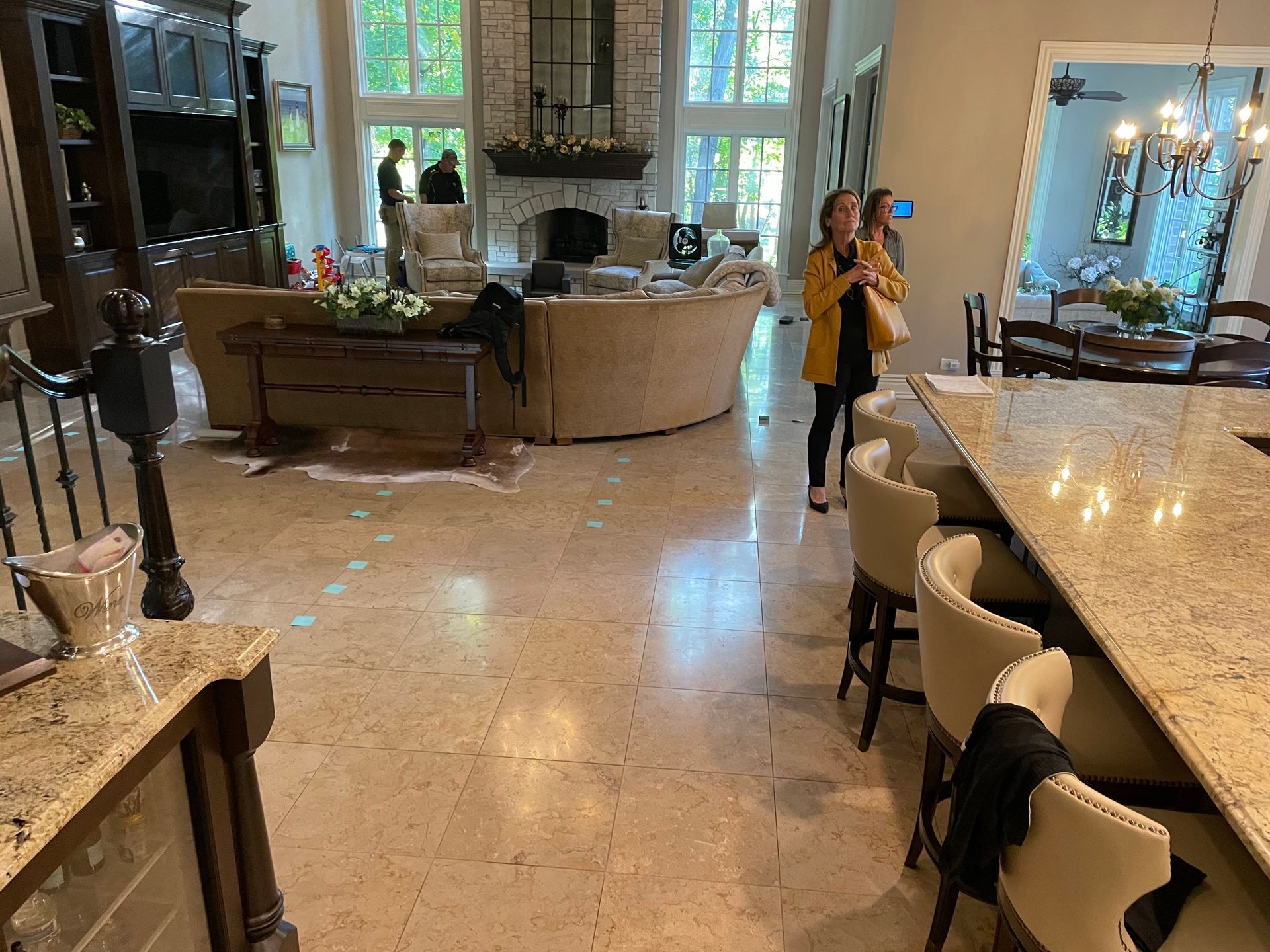 Spacious living room with marble floors, sofa, fireplace, and a person in a yellow coat near the back.