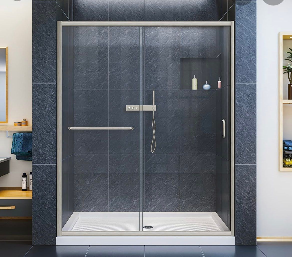 Glass shower enclosure with dark tile walls and chrome fixtures in a bathroom