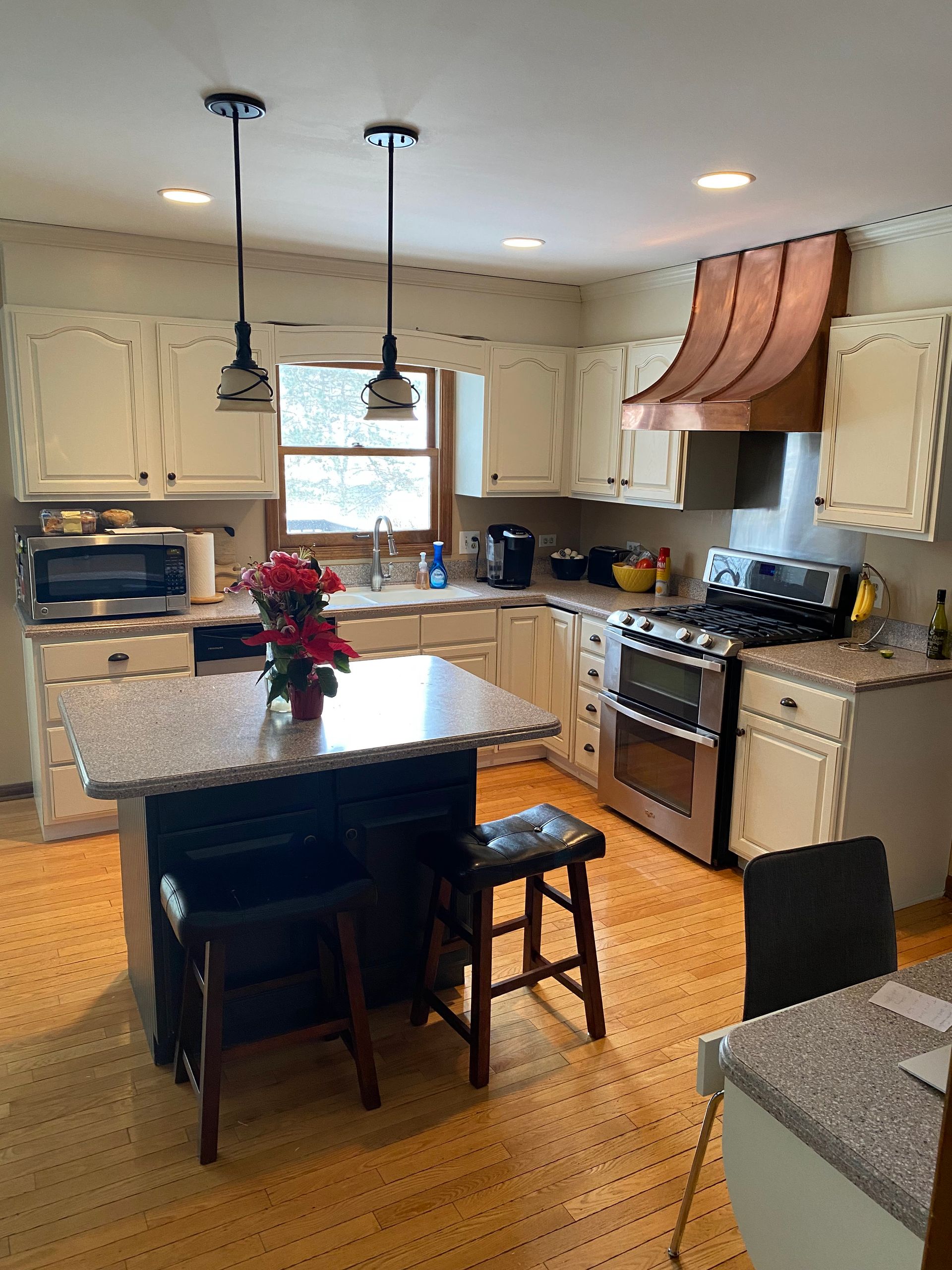 Bright kitchen with island, stainless steel appliances, pendant lights, and a window over the sink