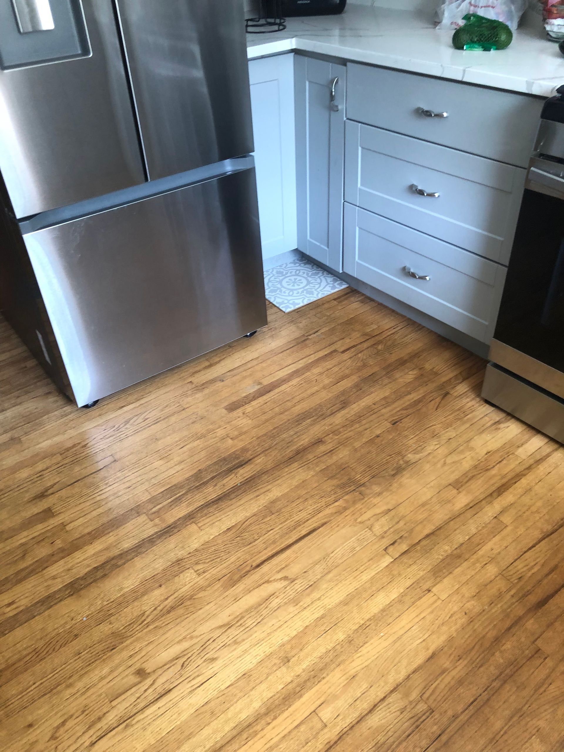 Kitchen with wood floor, stainless steel refrigerator, and white cabinets.