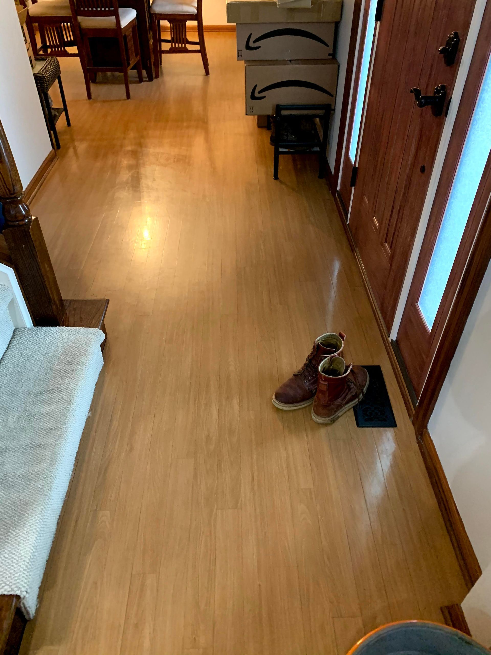 Hallway with wooden floor and a pair of shoes by a glass door, lit by warm indoor light