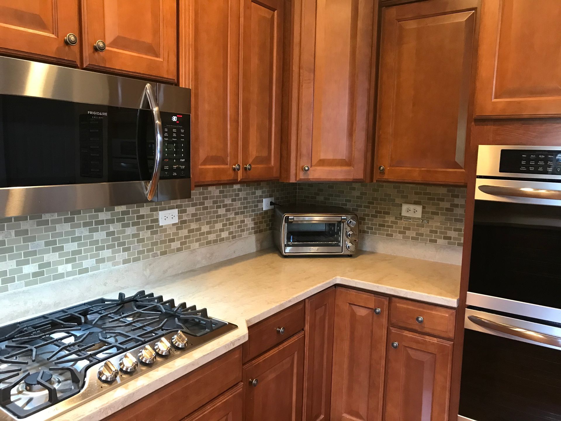 Modern kitchen with wooden cabinets, stainless appliances, gas cooktop, and tiled backsplash